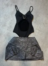 Body negro con escote halter, abertura en el abdomen y detalle metálico en el centro.