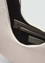 Bolso marrón con forma de media luna, asa corta y cierre de cremallera.