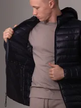 Campera Calvin Klein acolchada con capucha, color azul marino, cierre frontal con cremallera y bolsillos laterales con cremallera.