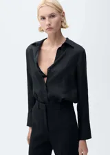 Camisa negra de lino con cuello camisero, manga larga con puños abotonados y cierre frontal con botones.