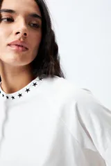 Remera negra de corte holgado con mangas ranglan y cuello redondo con bordado de estrellas blancas.