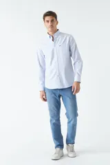 Camisa oxford celeste con rayas verticales blancas, de manga larga y corte regular. Tiene cuello abotonado, bolsillo en el pecho y logo bordado.