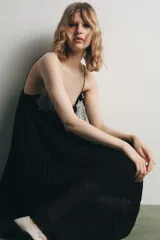 Vestido midi negro de tejido plisado, con escote pico, tirantes finos ajustables y aplicación de encaje y bordados florales combinados a contraste.