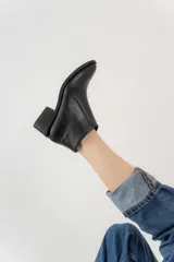 Bota corta negra de cuero, con punta fina y taco cuadrado.