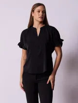 Blusa blanca de gasa marca Floral & Ivy, con cuello a la base y escote en V. Mangas cortas con elástico fruncido.