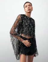 Top negro de tul con lentejuelas doradas y mangas largas acampanadas.