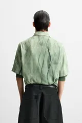 Camisa verde agua con estampado abstracto, corte relaxed fit, cuello solapa, manga corta y cierre frontal con botones.