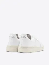 Zapatillas Veja V-10 de cuero blanco con logo lateral en forma de "V" y suela color crema.