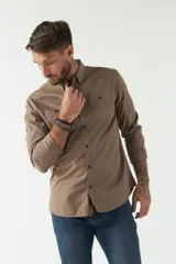 Camisa de hombre color marrón con efecto stone wash, fit regular, cuello americano, cierre con botones, dos bolsillos frontales con botón y mangas largas con puños abotonados.