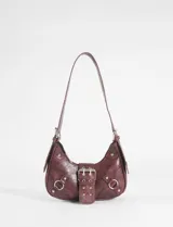 Cartera de hombro estilo baguette en color marrón con acabado texturizado. Presenta una hebilla frontal decorativa, detalles de herrajes metálicos plateados y correas laterales con argollas.