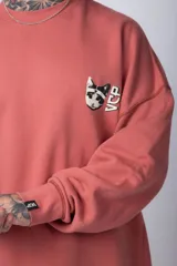 Buzo color crema de corte oversize confeccionado en tela friza con cuello redondo y puños y cintura acanalados. Presenta un pequeño bordado en el frente y un estampado grande en la espalda.