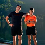 Remera deportiva naranja de poliéster y spandex, con logo Merrell estampado en el pecho.