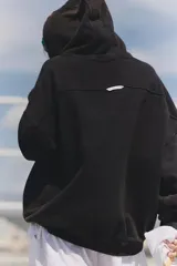 Buzo con capucha negro, de calce relajado y holgado, con costuras definidas, mangas ligeramente amplias y hombros caídos.