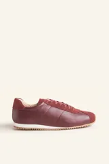 Zapatillas deportivas de cuero color borgoña con detalles en gamuza al tono, cordones finos y suela de goma blanca.