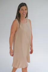 Vestido midi color beige, sin mangas, con escote redondo y volado en el ruedo.