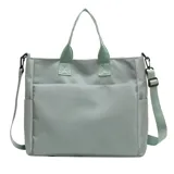 Bolso tipo tote color celeste con correa larga verde y asas cortas.