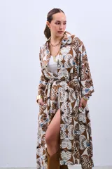 Camisola tipo vestido con estampado floral en tonos marrón, beige y celeste. Tiene cuello camisero, mangas largas y lazo para ajustar en la cintura.