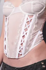 Corset lencero blanco de microtul y encaje, con tazas de encaje forradas con microtul y puntilla, aro metálico interno media copa, ballenas y breteles elásticos regulables. Acceso por espalda mediante ganchos corseteros.