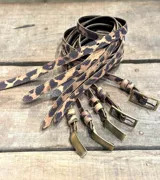 Cinto con diseño de animal print en tonos marrón y negro, hebilla metálica en dorado.