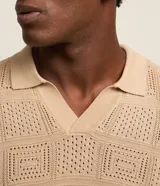 Remera polo de manga corta color beige, con cuello inglés y textura patchwork en cuadrados.