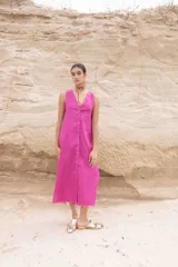 Vestido largo fucsia de lino, sin mangas, con escote en V y abotonadura frontal.