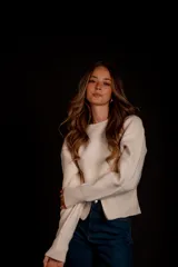 Buzo de punto color crema, con cuello redondo, cierre frontal y mangas largas.