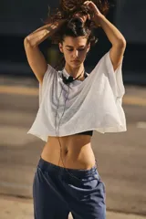 Camiseta deportiva blanca de tejido ligero y ventilado, con diseño holgado y espalda recortada.