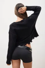 Sweater negro de tejido de punto con trenzas, corte crop y terminaciones desflecadas.