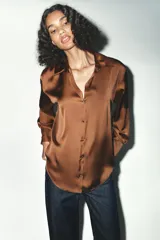 Camisa azul marino de satén, con cuello solapa, escote en pico y mangas largas con puños abotonados. Cierre frontal con botones.