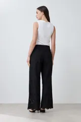 Pantalón negro de corte amplio con bordado de boderie y lazo de ajuste en la cintura.