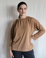 Remera color caramelo de corte holgado, con cuello redondo y mangas largas.