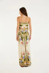 Pantalón de viscosa con estampado tropical de flores y hojas en tonos naranja, amarillo, verde y violeta sobre fondo blanco. Tiene cintura alta con elástico y cordón ajustable con borlas.