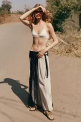 Pantalón bombacho marrón de tejido fluido, tiro medio con cintura elástica ajustable con cordones, bolsillos laterales ocultos y bajo abullonado con elástico interior.