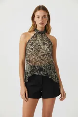 Top sin mangas con estampado abstracto en tonos negro, gris y beige. Presenta cuello halter con abertura en la espalda y cierre con botón.