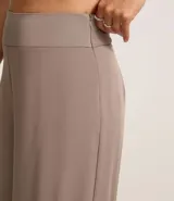 Pantalón pantalona color borgoña, confeccionado en crepé, con cintura ancha, cierre lateral y pliegues.