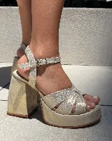 Sandalias de plataforma color rojo charol, con tiras cruzadas en el empeine, pulsera al tobillo con hebilla metálica y tacón cuadrado.