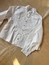 Camisa blanca de mangas largas con cuello alto y detalles de encaje.