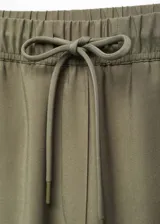 Pantalón color verde oliva, de tejido fluido, corte recto, tiro alto, cintura elástica con cordón de ajuste y bolsillos laterales.