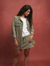 Sobrecamisa celeste de denim con cuello camisero, cierre frontal con botones a presión, bolsillos con solapa en el pecho y mangas largas con puños abotonados.