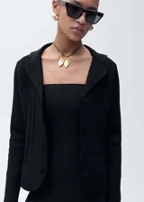 Chaqueta negra de punto con cuello de solapa, cierre frontal con botones, diseño entallado y manga larga.