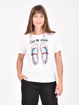 Remera blanca de manga corta con cuello redondo y un estampado frontal que simula un par de zapatos de vestir a rayas rojas y blancas con detalles azules, acompañado del texto "Own the streets".