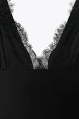 Vestido midi negro de tirantes con escote en pico y detalle de encaje en el escote.