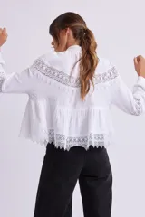 Blusa blanca de manga larga con cuello alto y detalles de encaje.