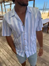 Camisa celeste y blanca a rayas verticales, de manga corta y corte recto.