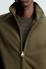 Sobrecamisa verde militar de tejido polar, corte regular fit, cuello alto, manga larga, bolsillos laterales y cierre frontal con cremallera.