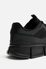 Zapatillas deportivas negras con capellada de tejido técnico transpirable y suela gruesa.