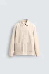 Sobrecamisa color beige de algodón con estructura canvas, corte relaxed fit, cuello solapa, manga larga con puño abotonado, bolsillos de plastrón frontales y cierre frontal con botones.