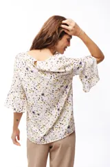 Blusa estampada con manchas abstractas en tonos lila, amarillo y negro, con mangas 3/4 acampanadas.