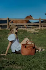 Bolso tipo tote de cuero color marrón con diseño tejido. Tiene bolsillo interno, porta llaves y cierre.