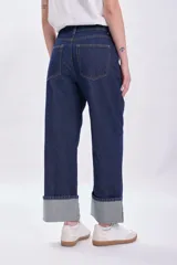 Pantalón de jean azul oscuro con bajo doblado.
